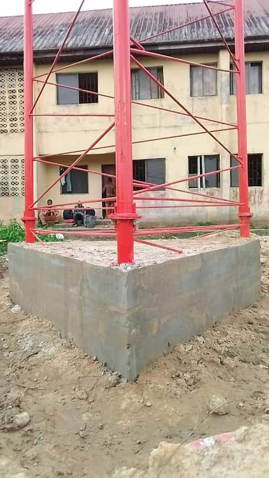 Freshly painted red tower base standing on a new concrete foundation in front of a building