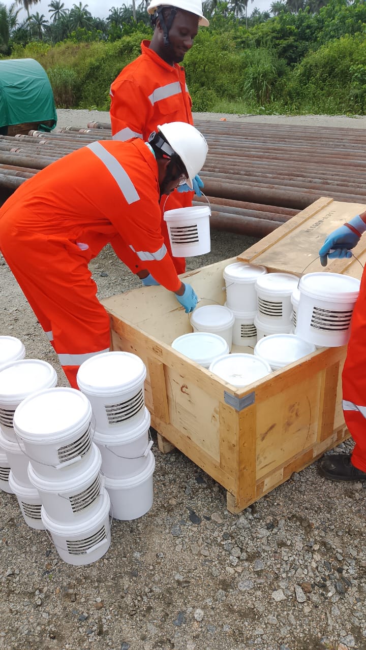 Workers in orange overalls loading site supplies into a wooden crate