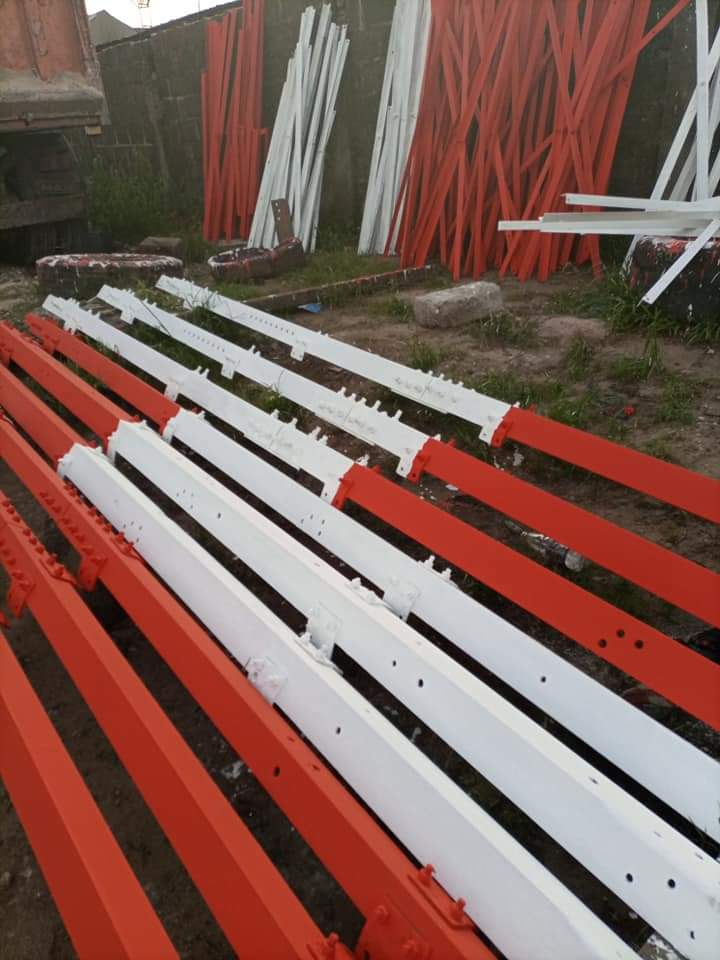 Rows of freshly painted red-and-white steel tower sections laid out on the ground
