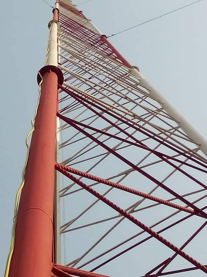 Close view of red-and-white lattice tower legs and bracing against a clear sky